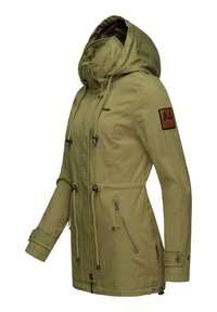 Olive green waterproof jacket with polka dot pattern, adjustable hood, drawstring waist, zip pockets, and logo patch on the sleeve.