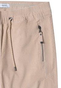 Beige byxor med elastisk midja, justerbar dragsko och metallisk dragkedjeficka. Slät textur med sydda detaljer.