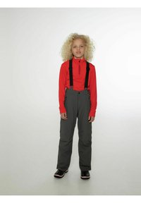 Rode lange mouw top met een rits en logo, gecombineerd met grijze sneeuwbroek met verstelbare zwarte bretels. Zwarte laarzen met rode accenten.