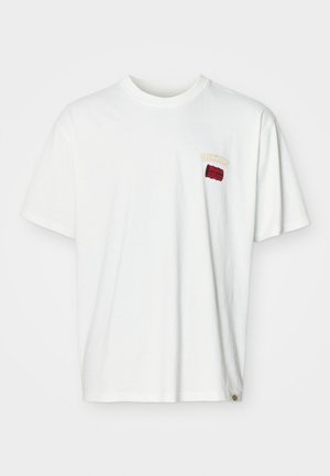 Bela bombažna majica s kratkimi rokavi, ki ima majhen vezen logotip v rdeči in rumeni barvi blizu levega prsnega dela. Okrogla izreza in sproščen kroj.