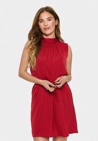 Robe sans manches rouge avec un col montant, taille à cordon et coupe décontractée. Tissu lisse avec un léger éclat, adaptée pour un usage casual.