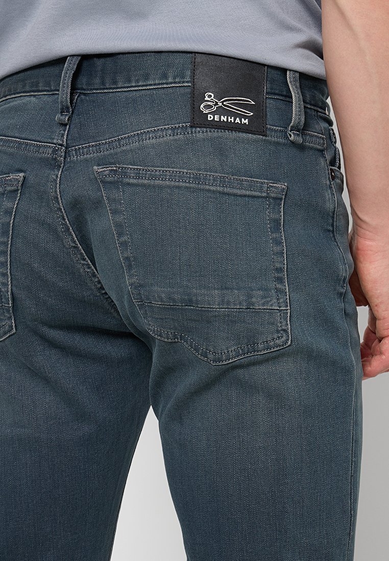 Denim jeans in een donkerblauwe wassing met een zachte structuur. Bevat een zwart merkembleem aan de achterkant, twee achterzakken en minimale stiksels.