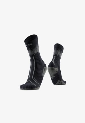 Chaussettes de sport noires et grises avec des accents à motifs, présentées en vues latérale et arrière sur fond blanc.