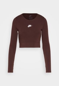 Mörkbrun långärmad cropped topp med rund hals och vitt Nike-logotyp centrerad på bröstet mot en ljusgrå bakgrund.