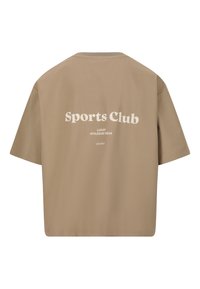 Ruskea, lyhythihainen t-paita, jossa on rento istuvuus. Takana on valkoisella painettuna "Sports Club" ja "Luxury Athleisure Wear".