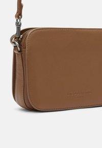 Borsa a tracolla in pelle marrone con texture liscia, chiusura con zip e dettaglio del logo embossato sulla parte frontale. Forma rettangolare compatta.