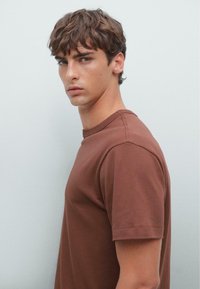 Bruin katoenen t-shirt, rondhals ontwerp met korte mouwen, gladde textuur, voorzien van een ontspannen pasvorm en minimale stiksel details.