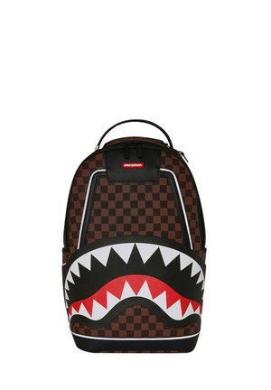 Mochila con patrón de tablero de ajedrez marrón y negro y un gran diseño de boca de tiburón en negro, rojo y blanco en el bolsillo delantero.