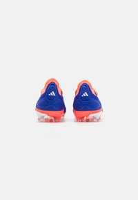 Blauwe voetbalschoenen met een oranje accent, voorzien van een textuur en een witte zool, ontworpen voor grip met zichtbare noppen.