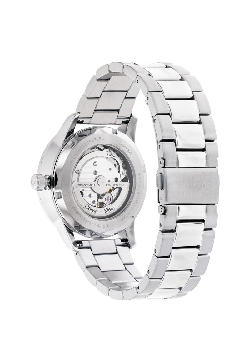 Reloj de pulsera Calvin Klein de acero inoxidable con fondo de caja transparente que muestra el movimiento automático y correa de metal.