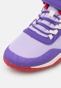 Scarpa sportiva viola con tomaia in rete, dettagli in vernice e suola rossa. Presenta lacci bianchi e superficie testurizzata per una migliore aderenza.