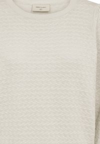 Lichtbeige sweater met een getextureerd zigzagpatroon, ronde hals en ribgebreide zoom. Gemaakt van een zachte breimateriaal. Label zichtbaar bij de halslijn.