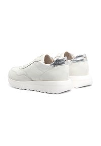 Białe skórzane sneakersy z teksturowanym wykończeniem, srebrne akcenty na pięcie i masywna biała gumowa podeszwa z wzorem w zygzak.