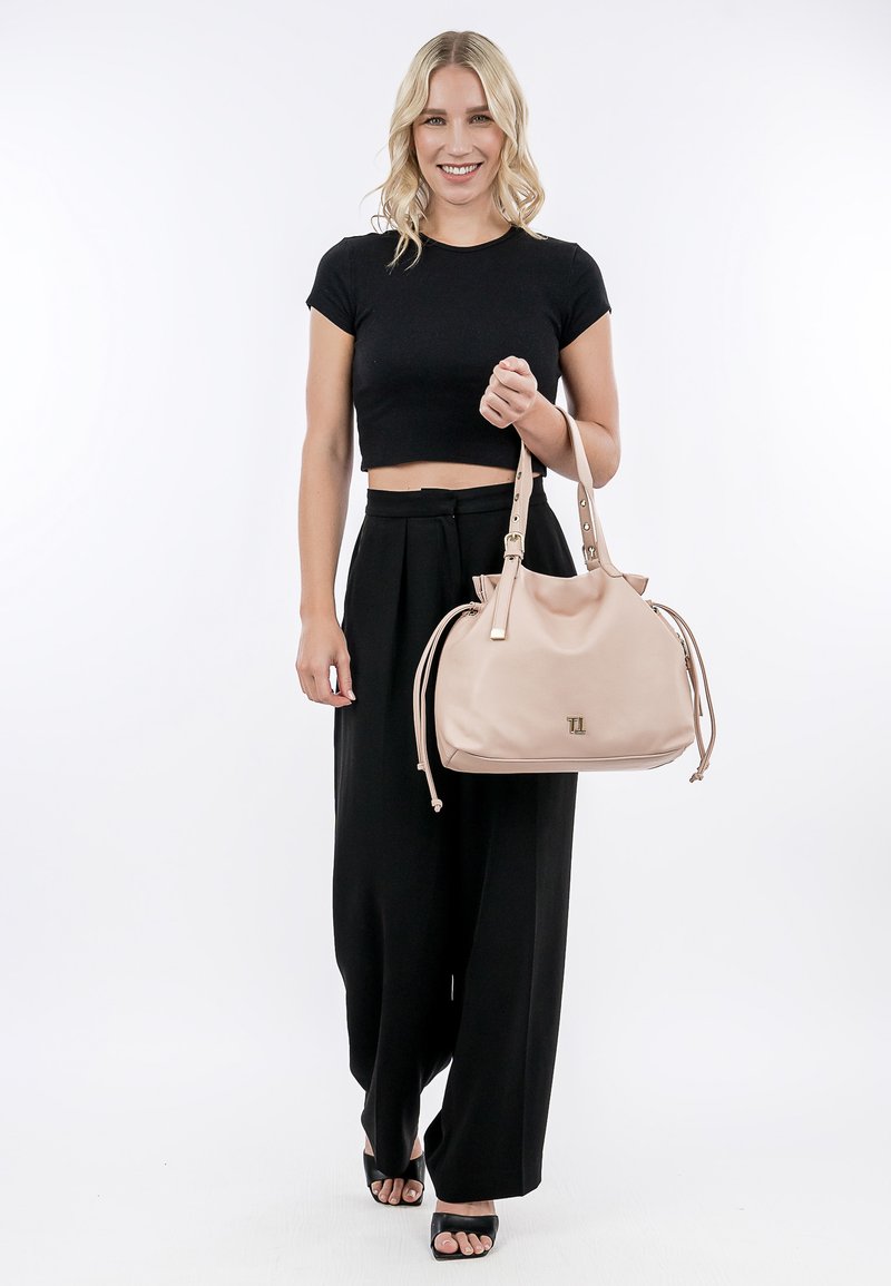 Różowa torebka z regulowanymi podwójnymi paskami i złotymi akcentami. Miękki, teksturowany materiał z delikatnym logotypem marki z przodu.