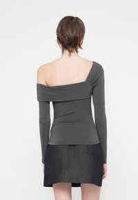 Šedý dlouhý rukáv top bez ramínek s detailem na nařasení, spárovaný s černou mini sukni z denimu s kapsami a rovnými okraji.