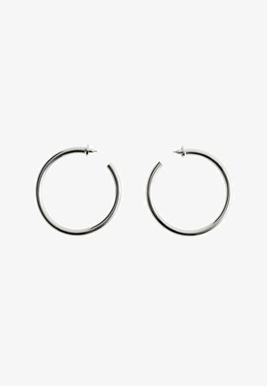 Par zlatnih srednje velikih srebrnih obruča s postom i zatvaračem na bijeloj pozadini.