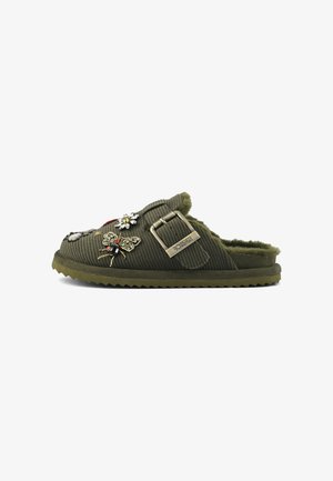 Olive green corduroy slip-on mule with faux fur lining, decorative jeweled insect and flower patches, and an adjustable brass buckle strap.