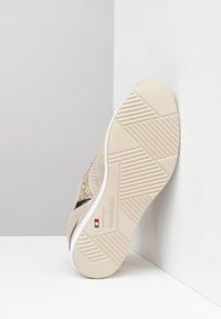 Tan and gold sneaker with a textured upper, white rubber sole, and contrasting black band. Features zigzag tread design and brand logo.