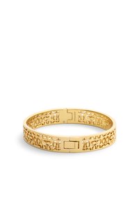 Pulsera de brazalete de oro con patrón recortado, acabado metálico suave, cierre de bisagra, y detalle de logotipo grabado. Forma circular, diseño ligero.