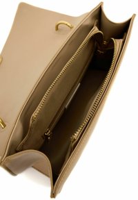 Beige leren tas interieur met twee ritscompartimenten en een open sectie, voorzien van goudkleurige hardware en een gladde textuur.