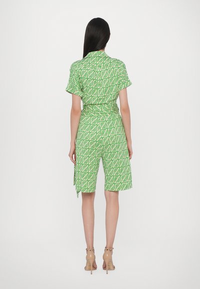 Robe verte à motifs avec des manches courtes, ornée d'un design feuillu. Ceinturée à la taille, elle a une coupe décontractée et des shorts jusqu'aux genoux.