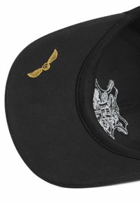 Gorra negra con alas doradas bordadas en la parte frontal. Presenta detalles plateados en el lado y un visera estructurada y curvada.
