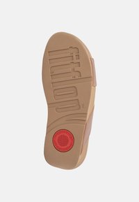 Beige rubberen sandaalzool met textuur voor grip, gemold merklogo en een rode cirkelaccents. Gladde bovenkant met een minimalistisch ontwerp.