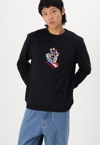 Felpa nera in cotone, con una grafica ricamata di una mano colorata e il testo "LANTA CRUZ" in rosso.