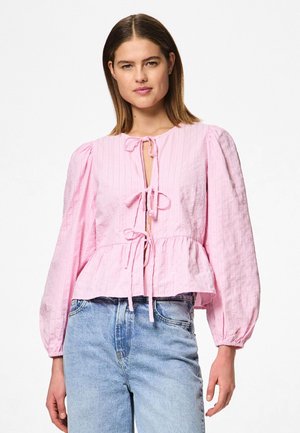 Blusa rosa de canalé con escote redondo, mangas largas abullonadas y un cierre con lazo en la parte delantera, que presenta un dobladillo tipo peplum y una textura suave.