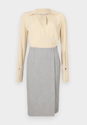 Beige indpakningsbluse med lange ærmer og grå blyantskirt, med en knapdetalje og glat tekstur. Klassisk kravedesign.