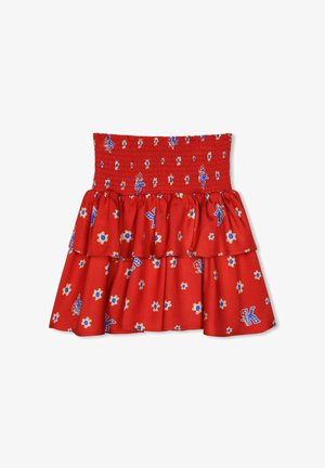 Jupe en coton rouge avec taille smockée, couches de volants et motif floral bleu agrémenté de petits accents décoratifs.
