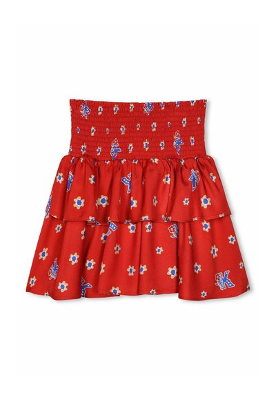 Jupe en coton rouge avec taille smockée, couches de volants et motif floral bleu agrémenté de petits accents décoratifs.