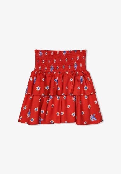 Jupe en coton rouge avec taille smockée, couches de volants et motif floral bleu agrémenté de petits accents décoratifs.
