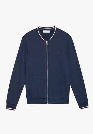Navy zip-up jacket made of soft fabric, features a ribbed collar with red and white stripes, two front pockets, and a small logo on the chest.