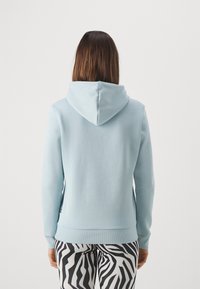 Felpa con cappuccio azzurro chiaro dallo stile rilassato, con polsini e orlo a costine. Abbinata a leggings con stampa zebra in bianco e nero.