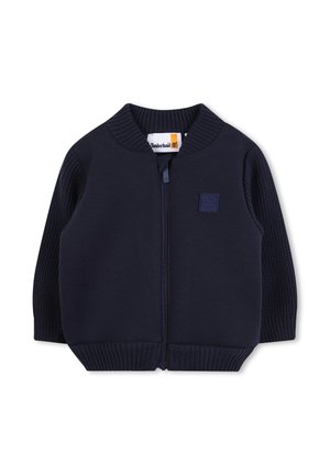 Pull zippé bleu marine avec des manches et un col côtelés. Présente un patch logo Timberland sur la poitrine. Fabriqué en tissu doux et texturé.