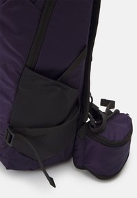 Purple backpack with black accents. Features a side pocket and adjustable straps, made from durable fabric with a textured finish.