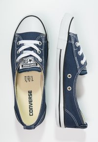 Baskets en toile bleu marine avec embout et semelle extérieure en caoutchouc blanc, dotées de lacets blancs, de détails noirs et du logo Converse sur la semelle intérieure.