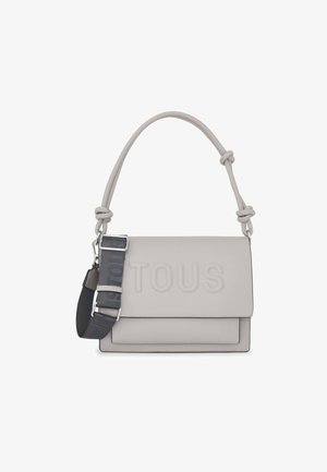 Sac à épaule en cuir gris avec une poignée nouée, logo "TOUS" gaufré et une bandoulière réglable à motifs. Texture lisse avec des bords nets.