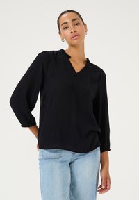 Zwarte blouse met lange mouwen, een V-hals en gerimpelde details bij de hals. Gemaakt van een gemeleerd stof, heeft het ingezette manchetten en een ontspannen pasvorm.