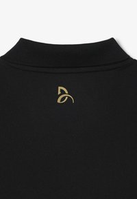 Czarna koszulka sportowa z prążkowanym kołnierzykiem i złotym logo na plecach. Gładki, teksturowany materiał. Minimalistyczny design.