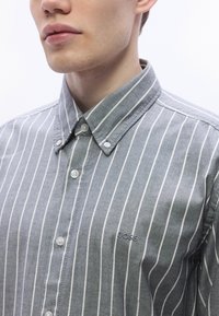 Szürke-fehér függőlegesen csíkos ing gombos gallérral, a mellrészen egy kis hímzett "BOSS" logóval. Puha tapintású.