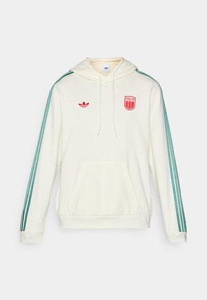 Krem majica s kapuljačom koja ima prednji džep, rukave sa zelenim prugama, te crveni talijanski simbol i adidas logo. Kapuljača sa vezicom i rebrasti manžetni.