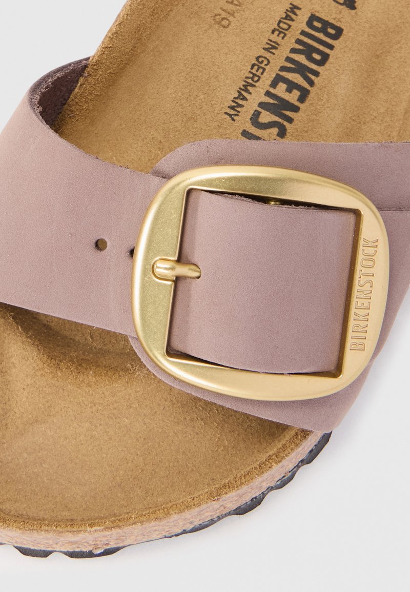 Lichtpaarse suède sandaal met een gouden gesp, gevormd kurken voetbed en zwarte rubberen zool. Opvallend logo in het voetbed gegraveerd.