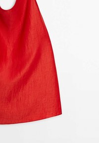 Robe rouge sans manches avec un col rond et un tissu texturé présentée sur un fond blanc.