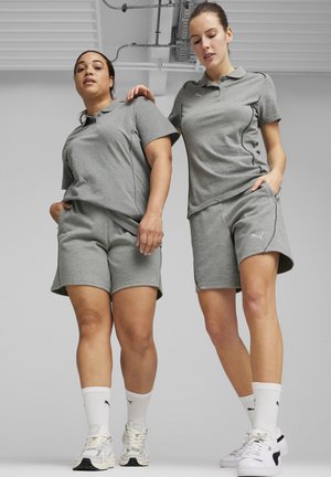 Deux mannequins portent des ensembles de sport gris assortis, comprenant des polos à manches courtes et des shorts, fabriqués dans un tissu doux, avec des accents de logo.