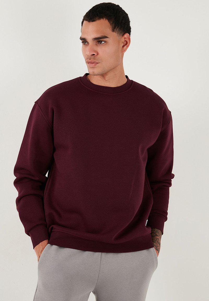 Bordeaux crewneck sweatshirt met lange mouwen, gemaakt van zachte stof. Ribgebreide manchetten en zoom, met een ontspannen pasvorm. Eenvoudig design.