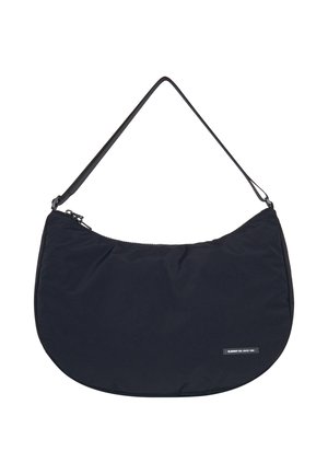 Schwarze Stoff-Schultertasche mit einer geschwungenen Form, Reißverschluss und einem schmalen Tragegurt. Auf der Vorderseite befindet sich ein kleines Logopatch.
