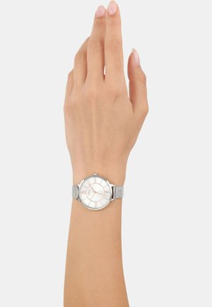 Silberne Armbanduhr mit rundem Ziffernblatt, weißem Zifferblatt, roségoldenen Akzenten und einem strukturierten Mesh-Armband, auf einer Hand präsentiert.