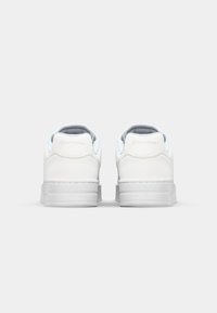 White leather sneakers with a smooth texture, featuring light blue accents and padded collar. Raised sole with logo detail on heel.